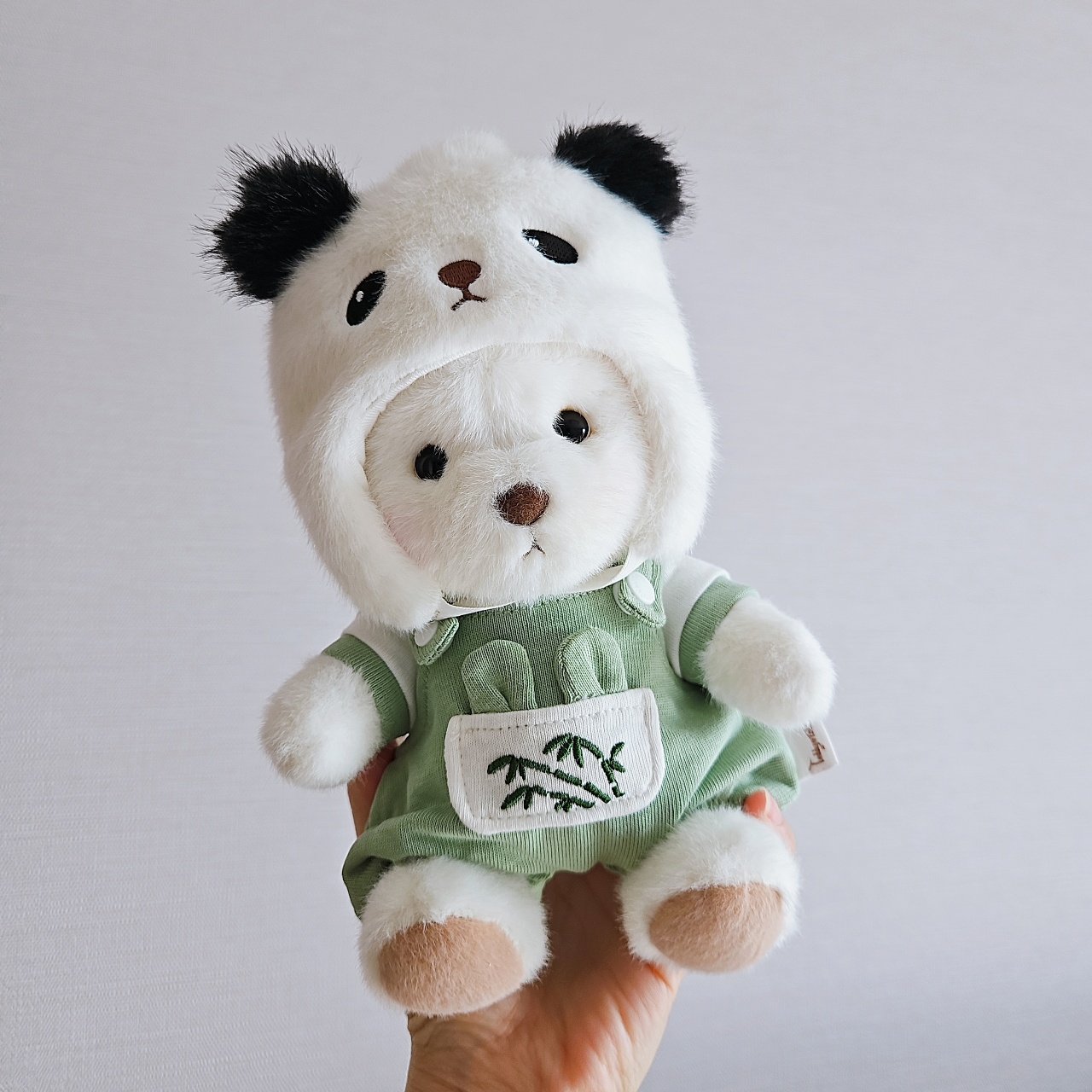 손에 들린 흰색 곰 인형과 팬더 모양 모자