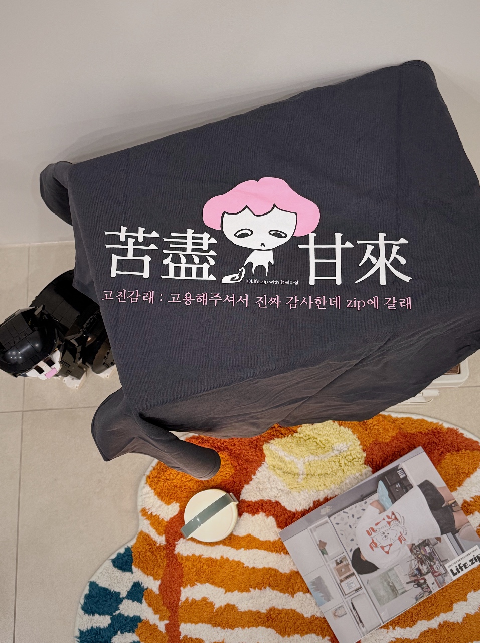 바닥에 놓인 그래픽 프린트 쿠션과 패턴 러그, 잡지