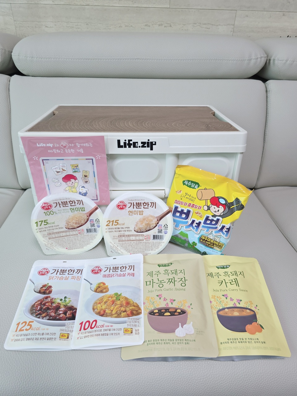 소파 위에 정렬된 라이프집 브랜드 밥, 반찬, 간식 제품들