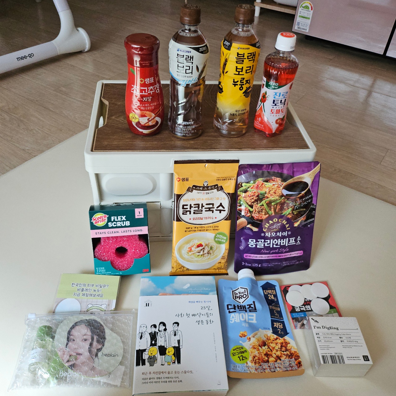 트레이에 정렬된 한국 소스병과 식품, 스크럽, 책, 면팩 등 생활용품