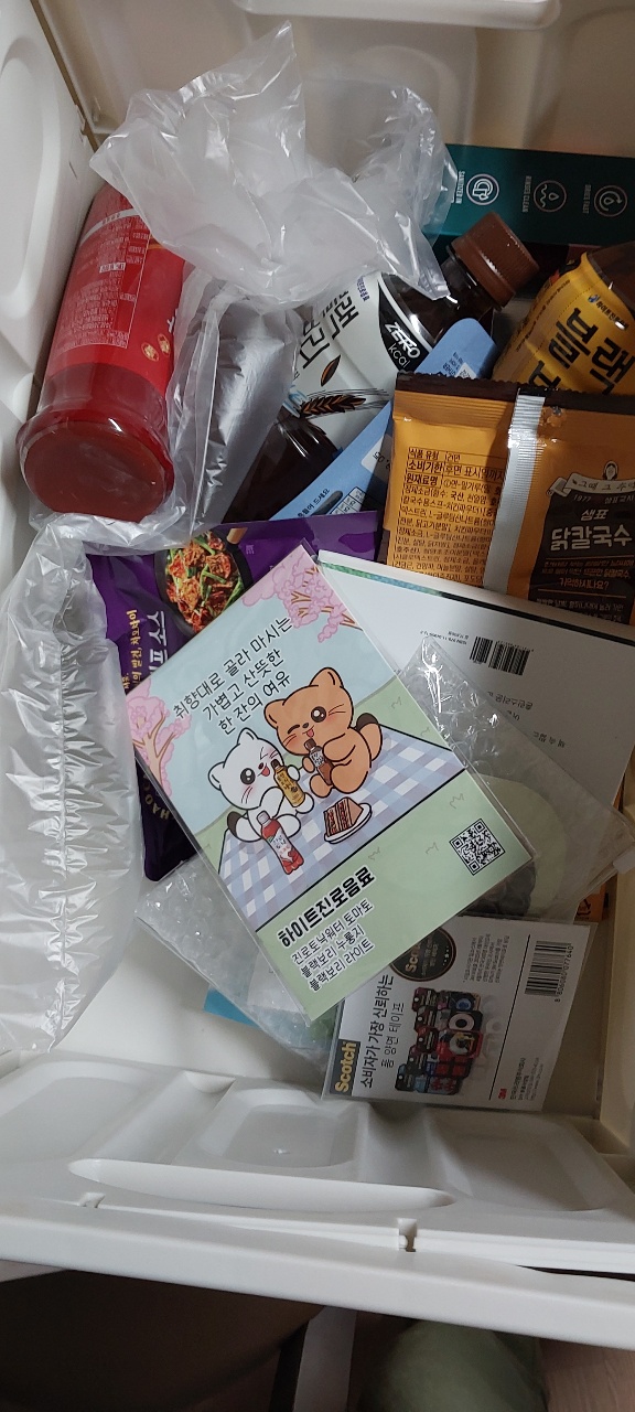 박스 안에 담긴 음료수, 간식, 잡지, 카드 등 배송 물품