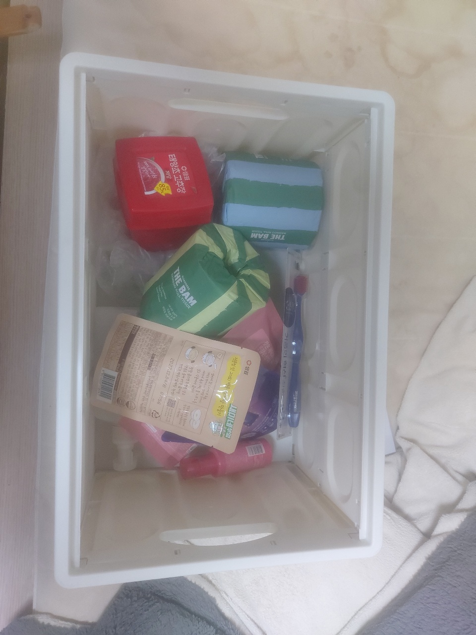 흰색 수납함에 정리된 음식 패키지와 생활용품
