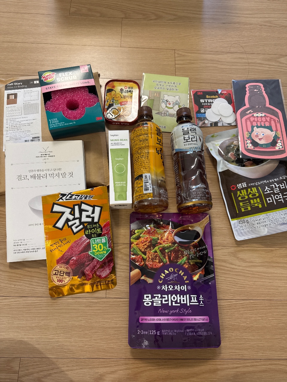 나무 바닥에 놓인 한국 식품과 간식, 음료, 생활용품 모음