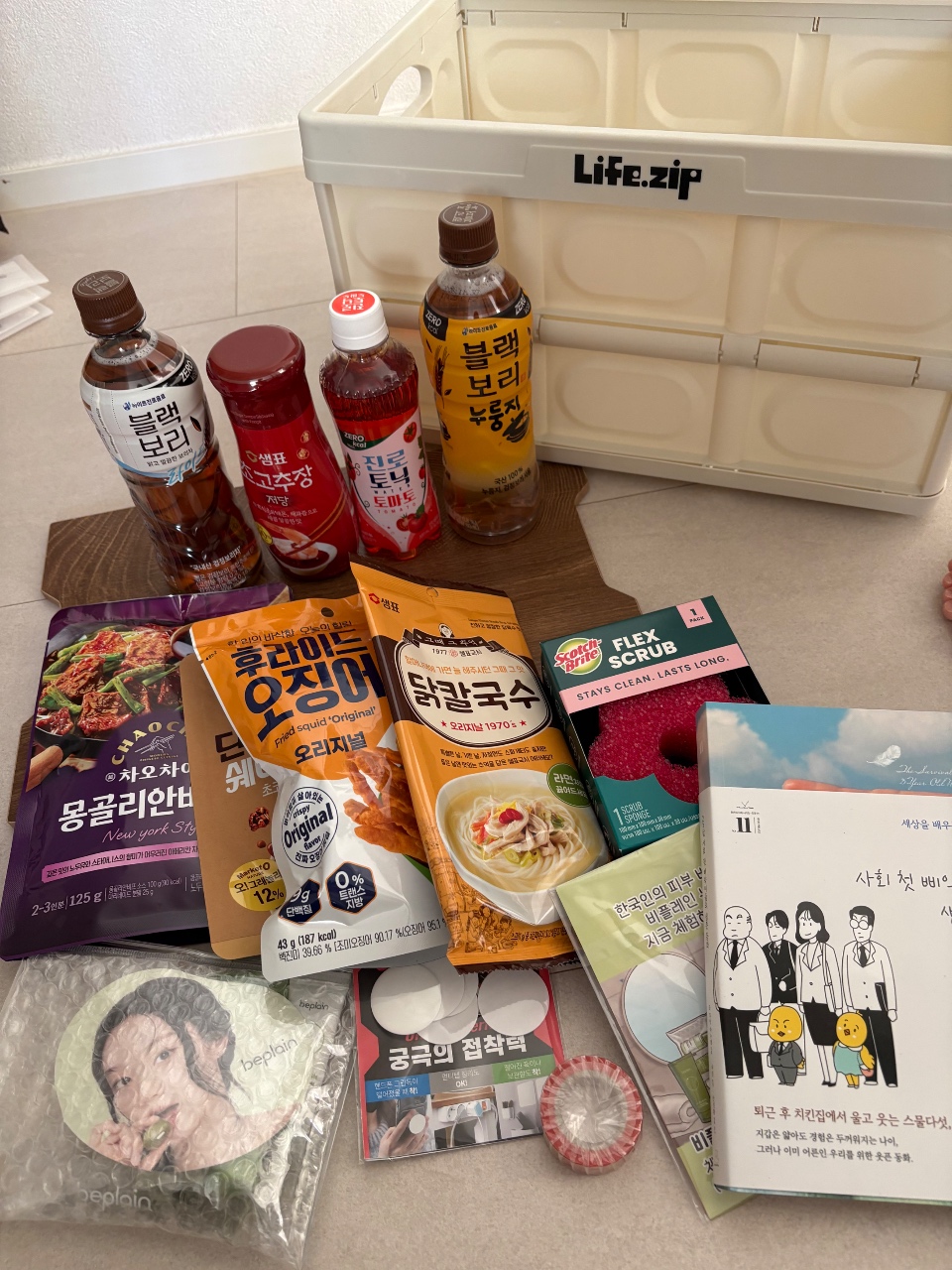 라이프집 수납함에 정렬된 음료, 라면, 책, 굿즈 등 생활용품