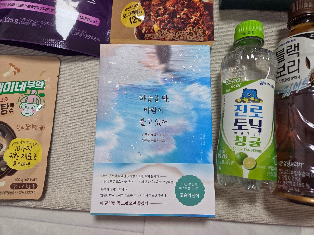 책, 음료수, 과자 등 생활용품이 식탁 위에 놓여 있다.