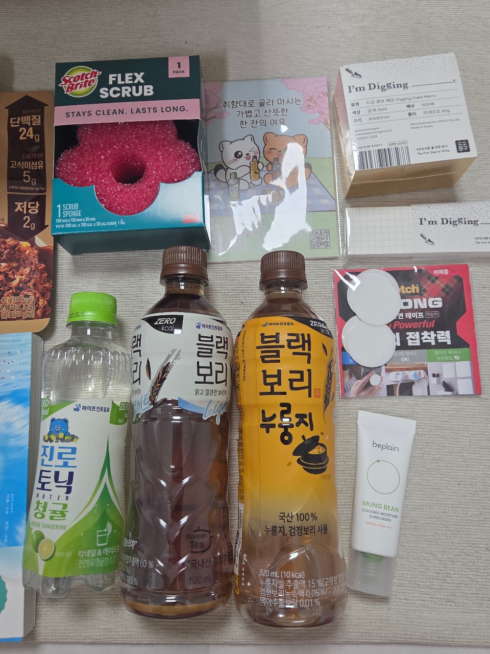 식탁에 놓인 음료수, 수세미, 카드게임, 스킨케어 제품 등 생활용품