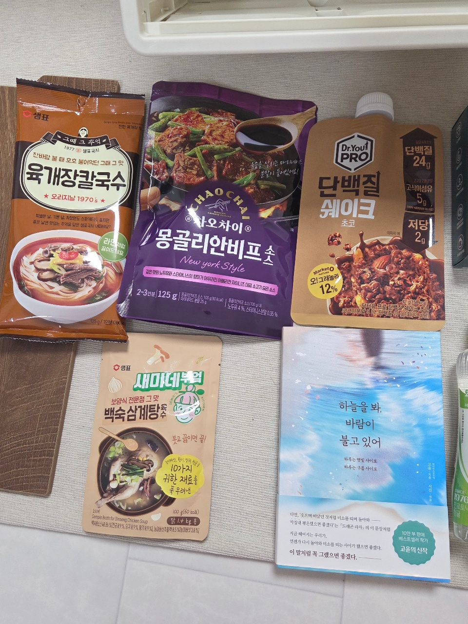 선반에 정렬된 라면, 소스, 케이크 등 간식과 책