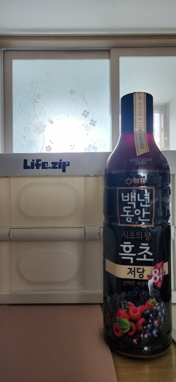 창가 선반에 놓인 검은색 병과 Life:zip 로고