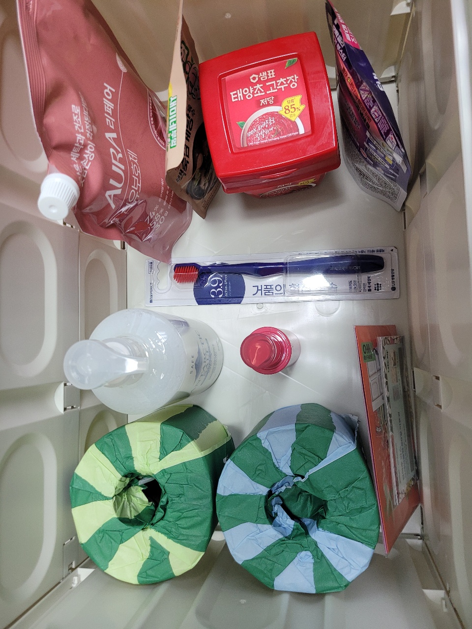 욕실 수건장에 정리된 세제, 칫솔, 샤워캡, 스킨케어 제품
