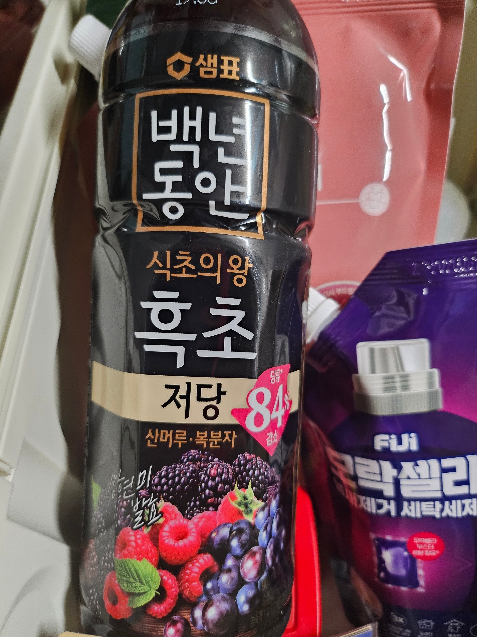 베리류 과일 이미지가 인쇄된 검은색 음료 병과 보라색 제품 패키지