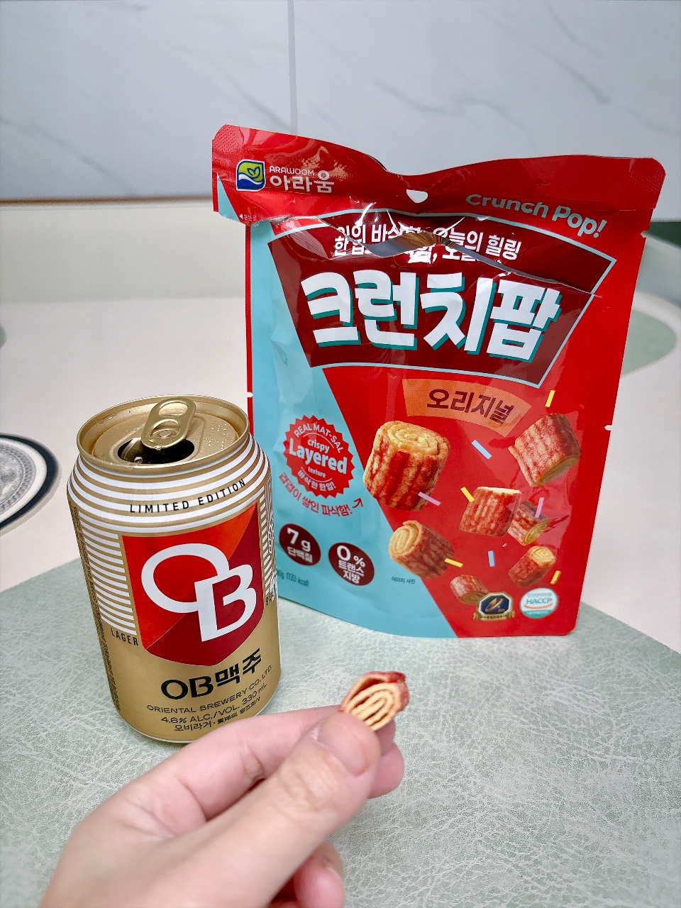 맥주캔과 스낵과자 그리고 과자를 들고 있는 손