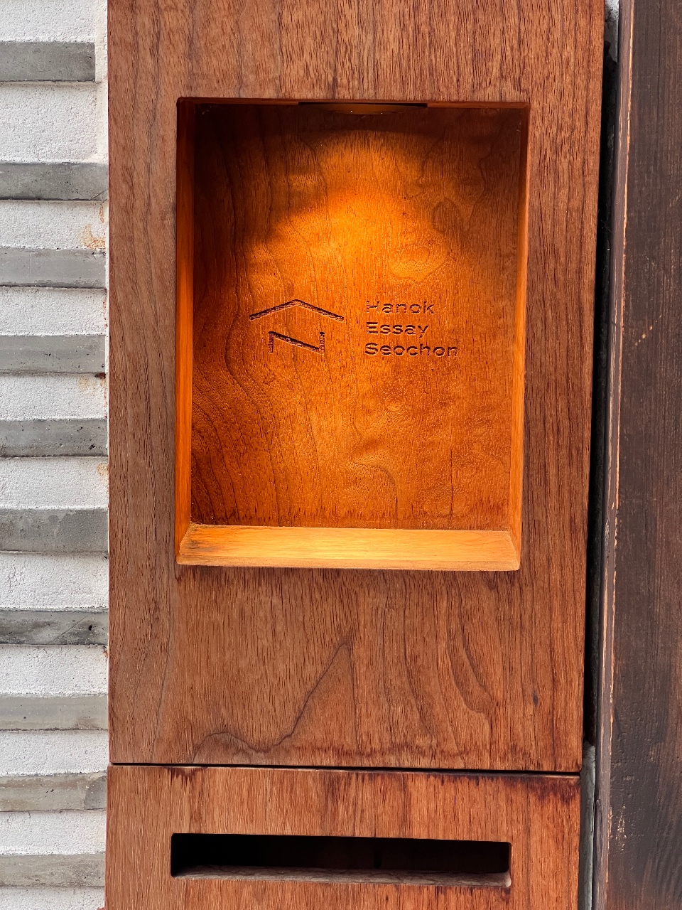목재 벽에 설치된 우편함과 초인종