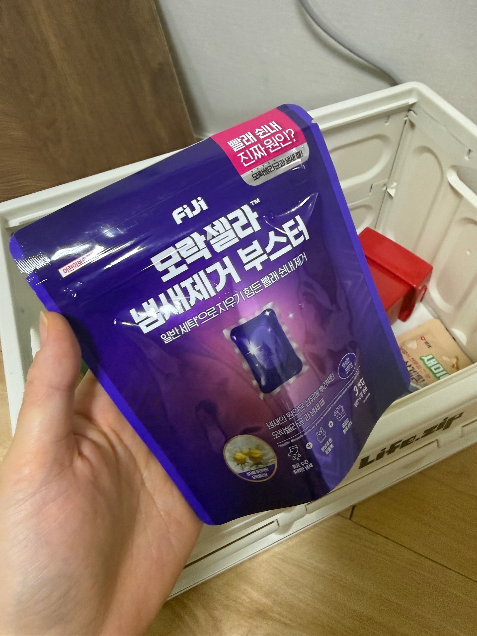 냉장고 서랍 위에서 들고 있는 FUJ 브랜드 부스터 팩 제품