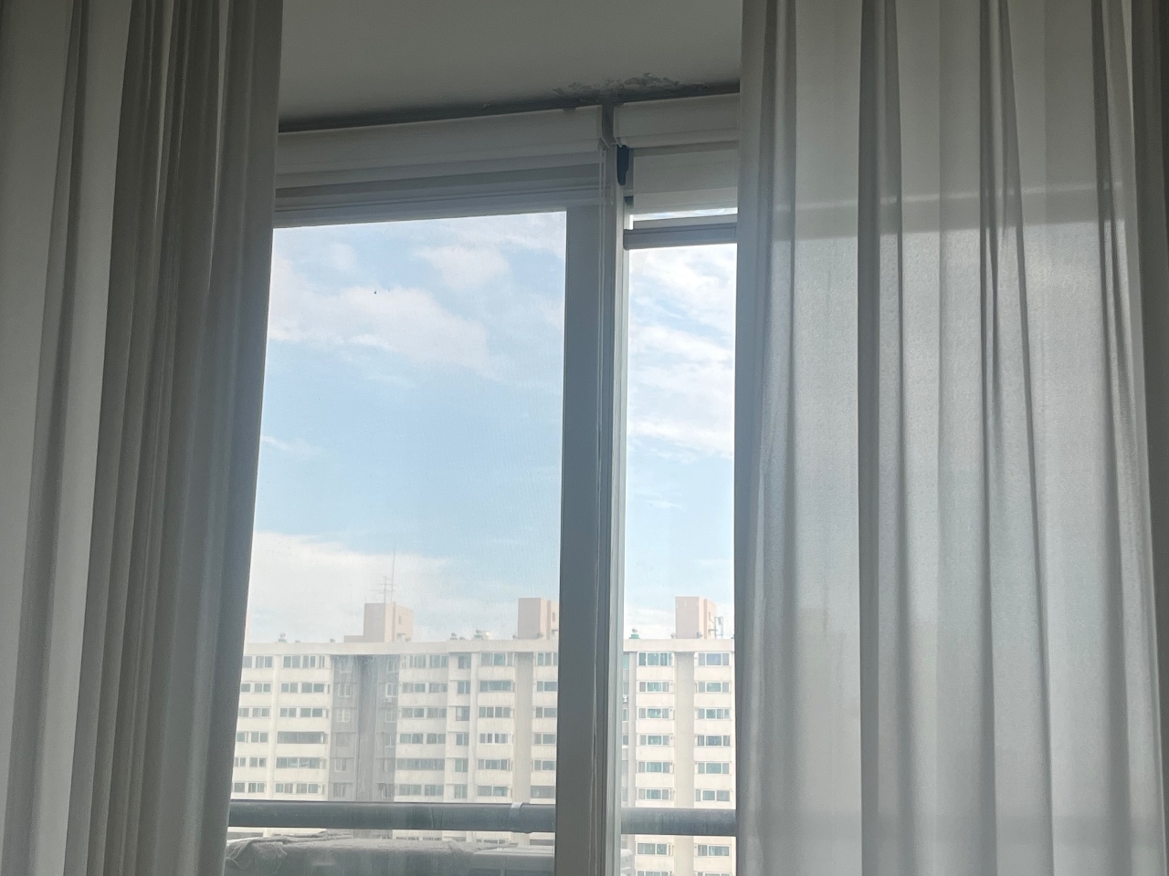 창문과 커튼 너머 보이는 도시 풍경과 아파트