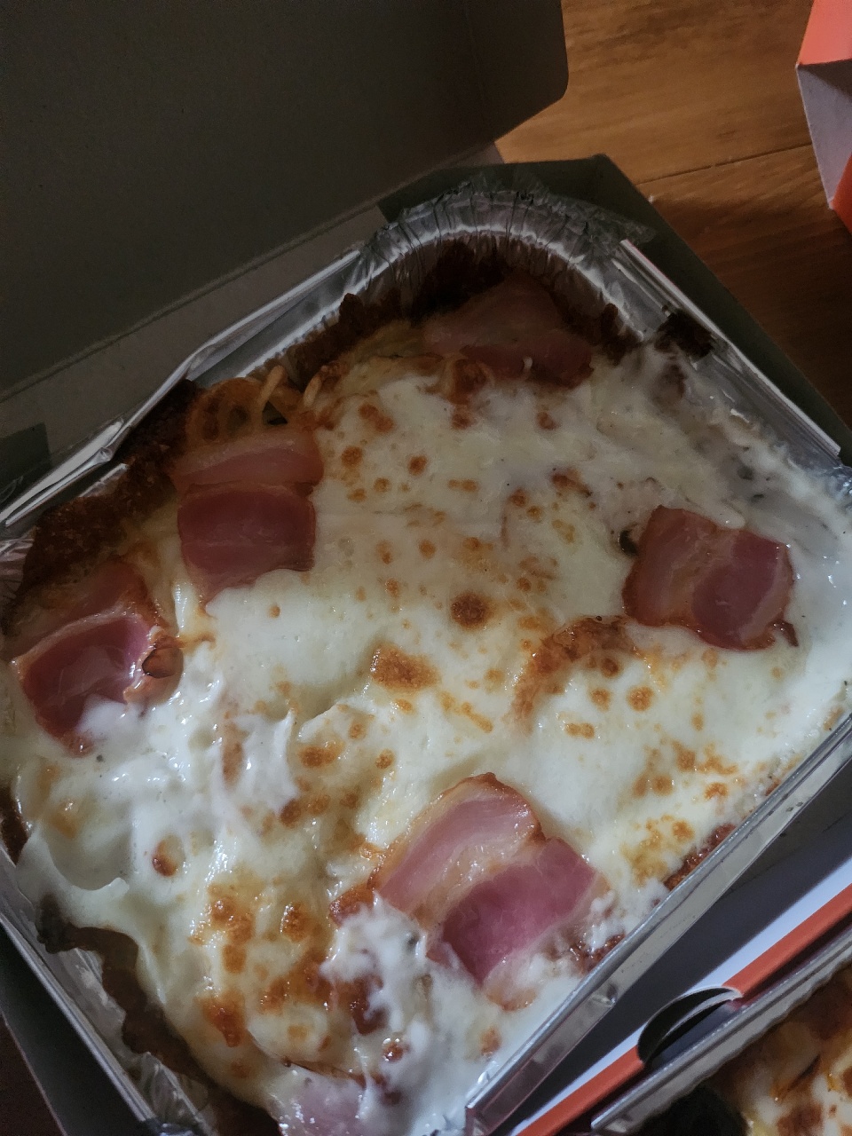 알루미늄 용기에 담긴 치즈와 햄이 올려진 피자
