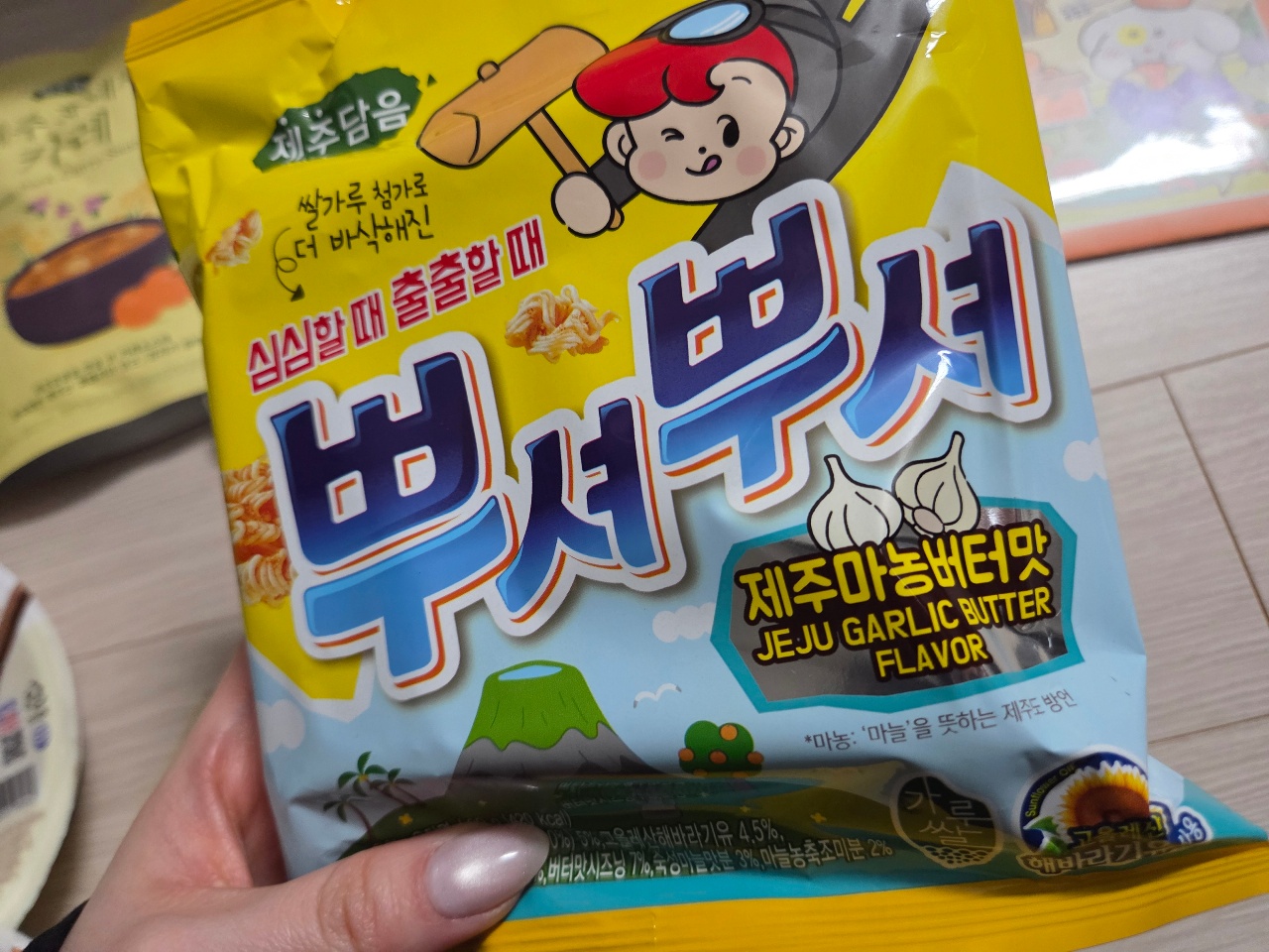 손에 들린 제주마늘버터맛 스낵 과자 봉지