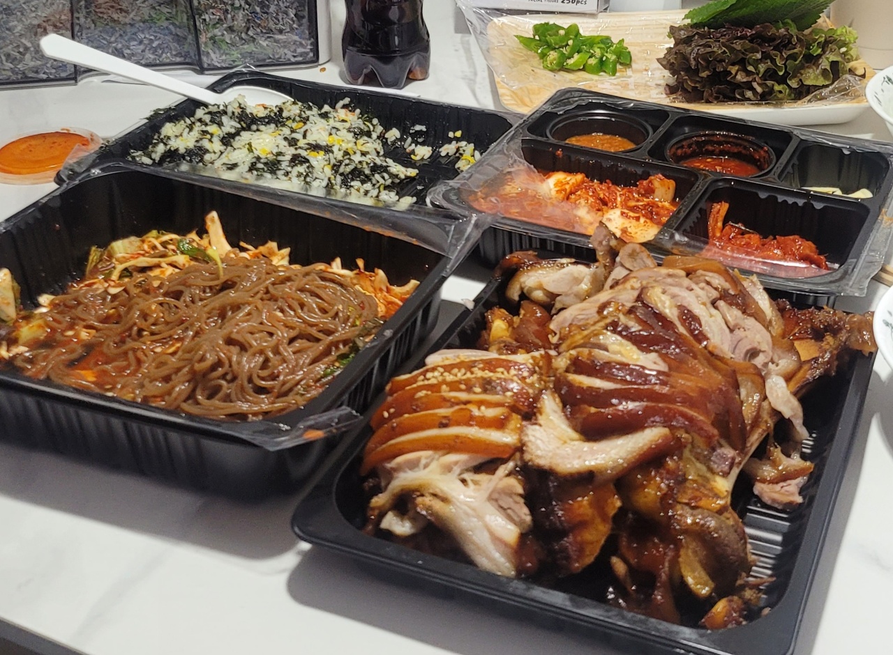 테이블에 차려진 국수, 고기, 밥, 반찬이 담긴 배달 용기들
