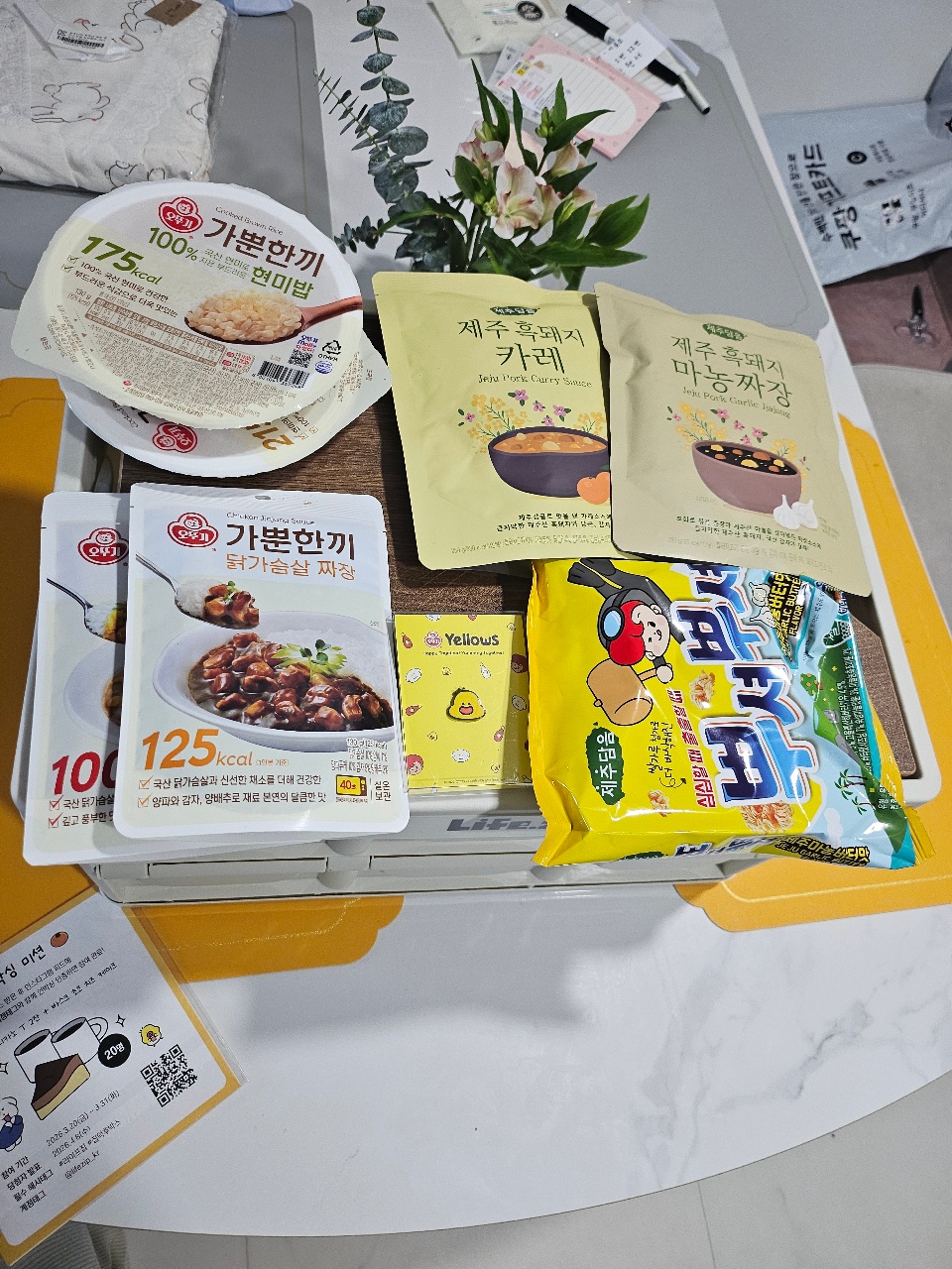 식탁 위에 놓인 한국 음식 패키지, 라면, 스프, 꽃과 물품들