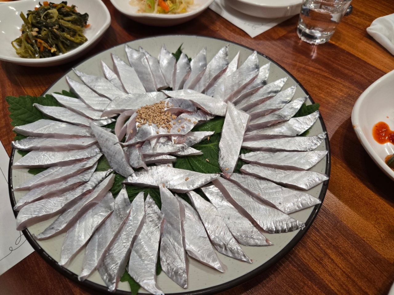 식탁에 차려진 슬라이스 생선회와 반찬
