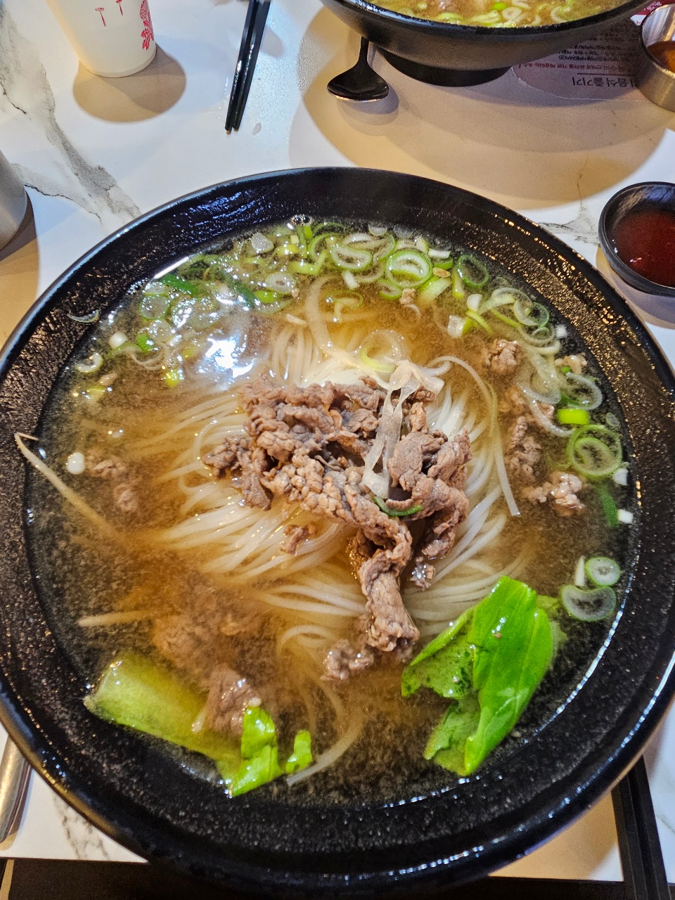 검은 그릇에 담긴 소고기, 국수, 청경채가 있는 라면