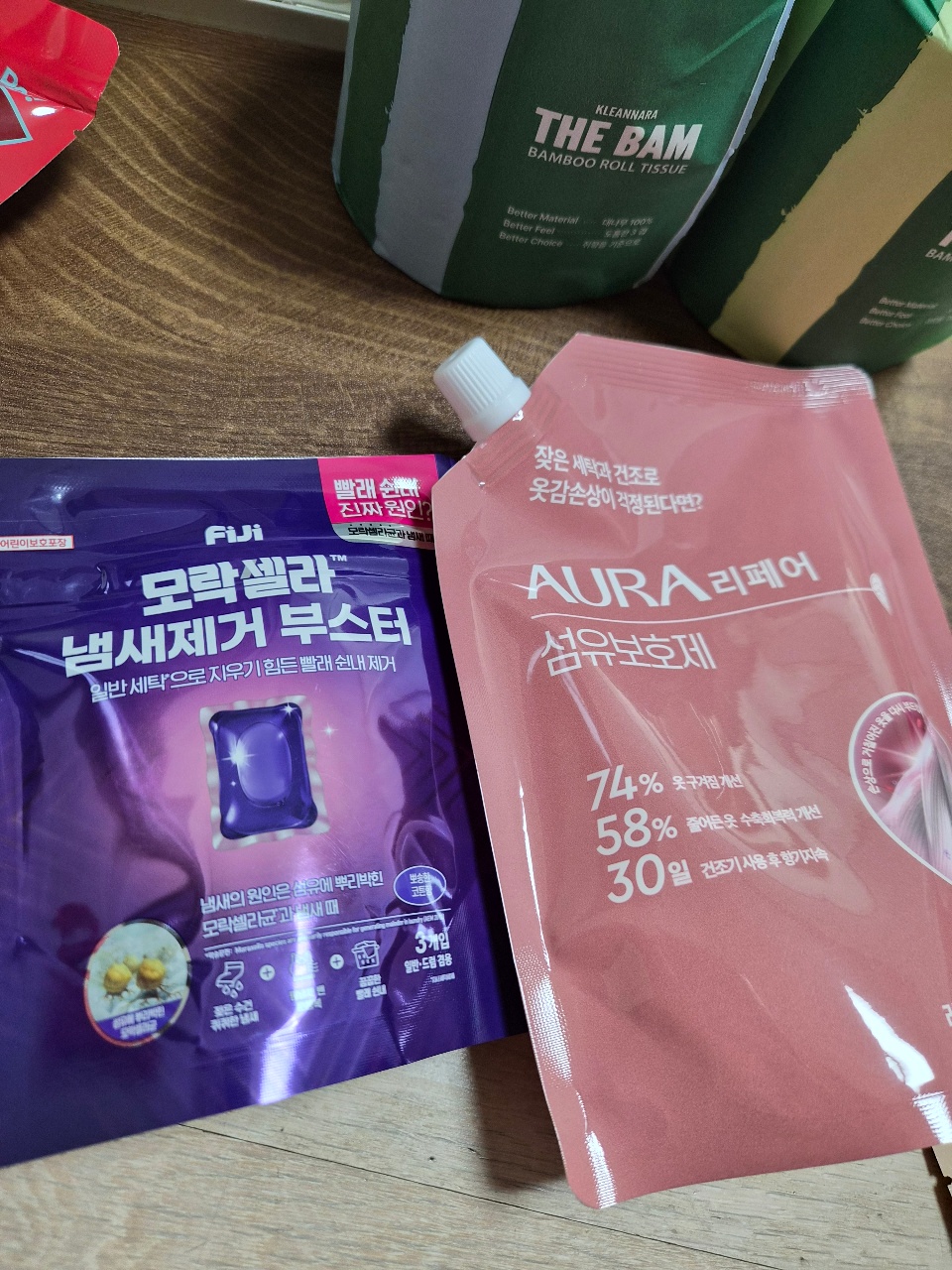 나무 바닥에 놓인 한글 표시 화장품 패키지와 티슈 상자