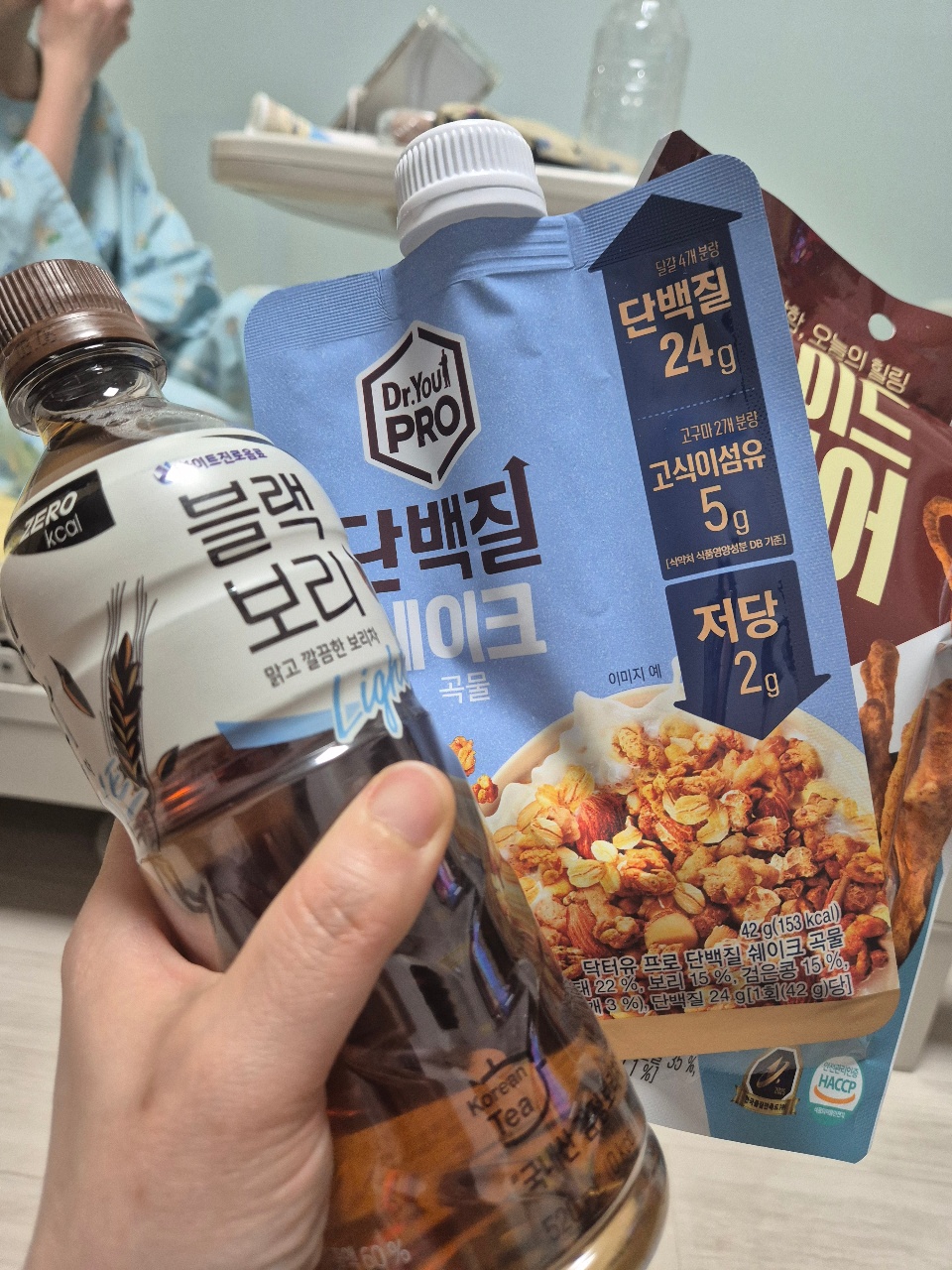 손에 들린 음료수와 시리얼바, 과자 등 간식 식품