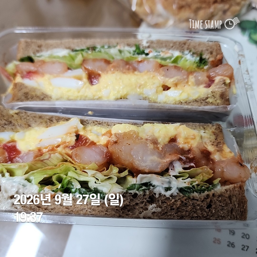 투명 용기에 담긴 계란과 햄, 야채가 올려진 샌드위치