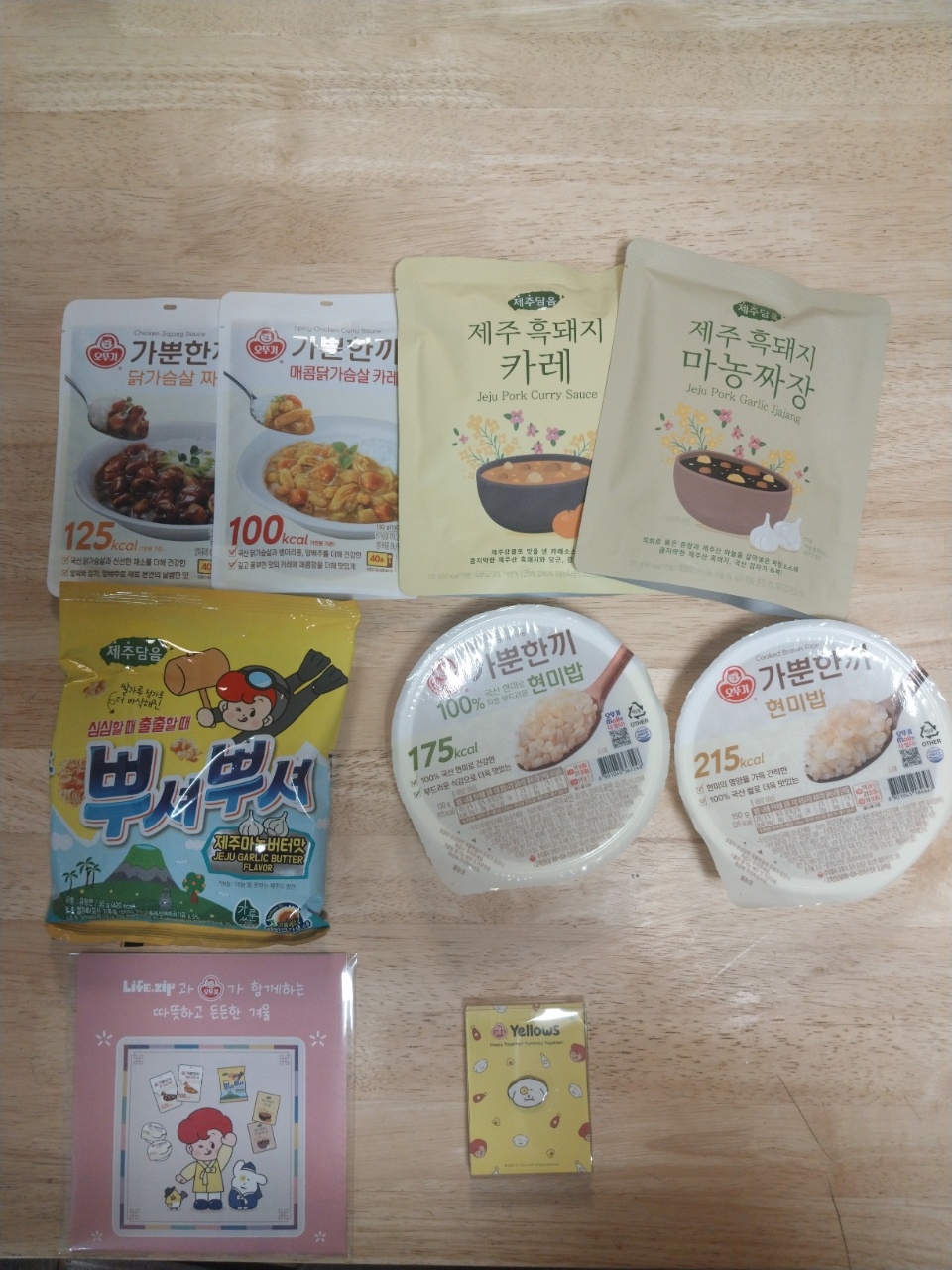 나무 바닥에 펼쳐진 한식 즉석밥과 카레 소스, 면 제품들