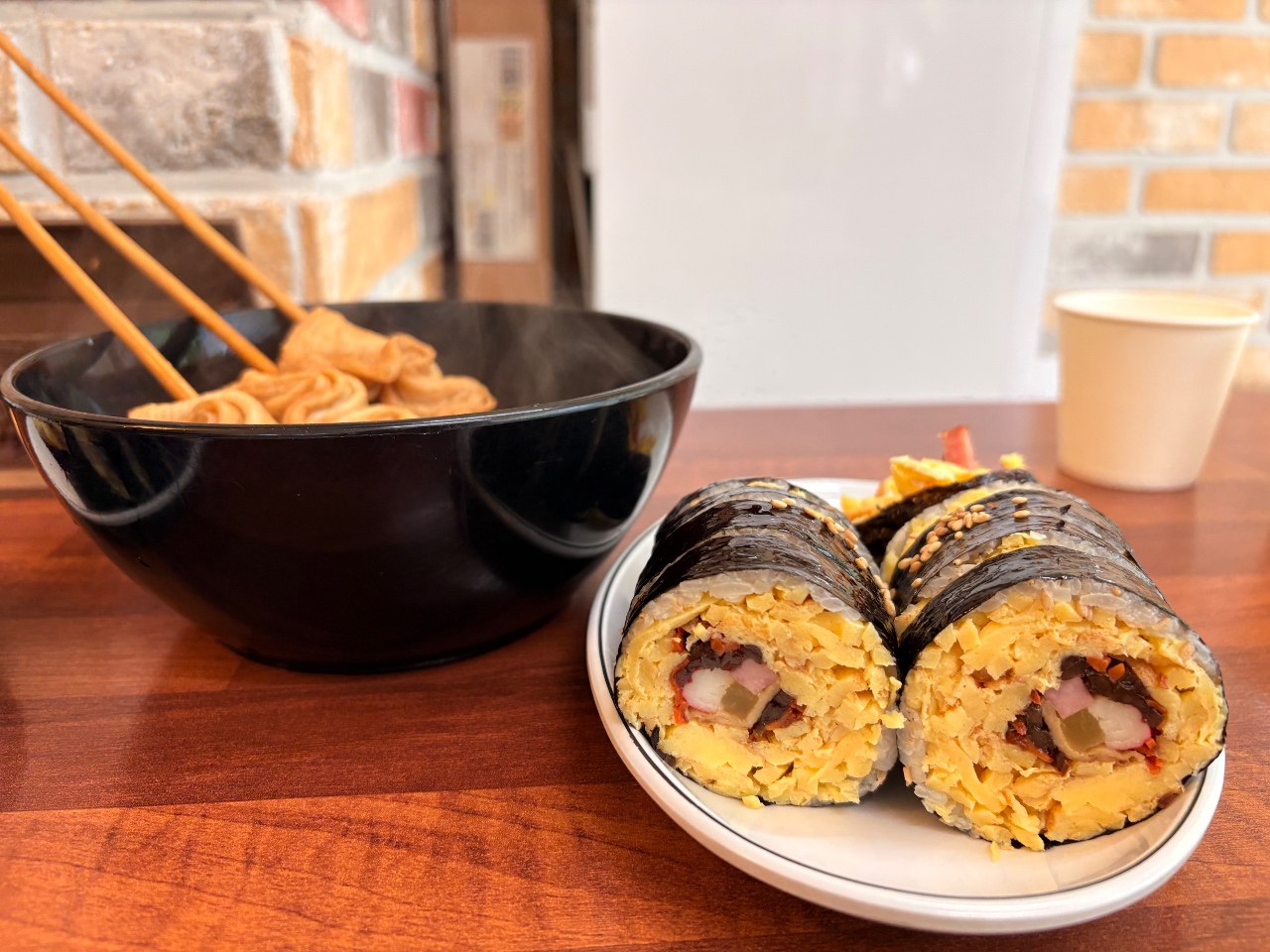 식탁에 차려진 김밥과 튀김, 젓가락이 놓인 검은 그릇