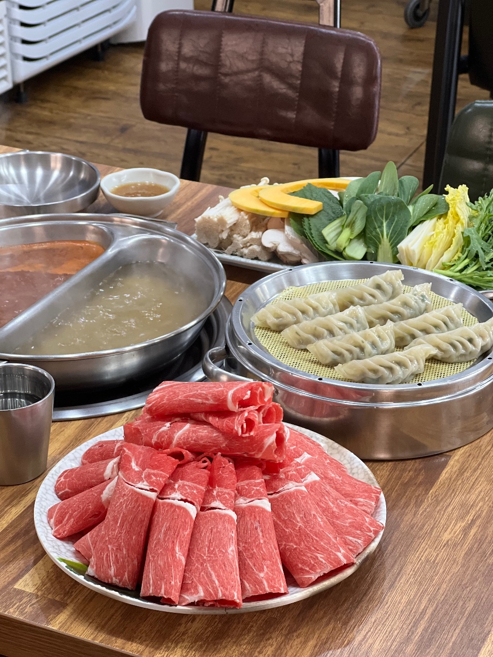 식탁에 차려진 소고기, 만두, 야채, 국물 요리
