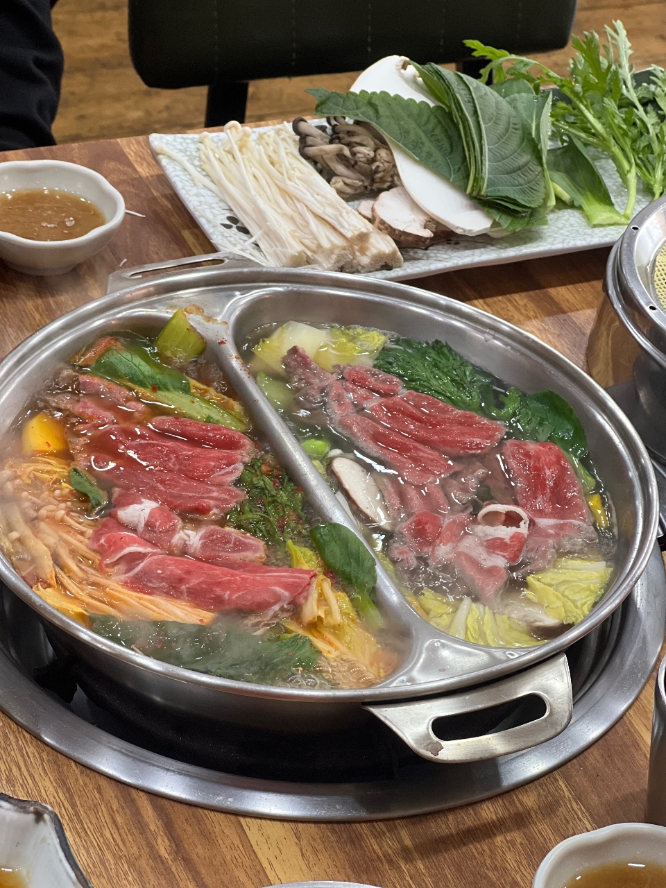 샤브샤브 냄비에 담긴 소고기와 채소, 곁에 쌈과 육수