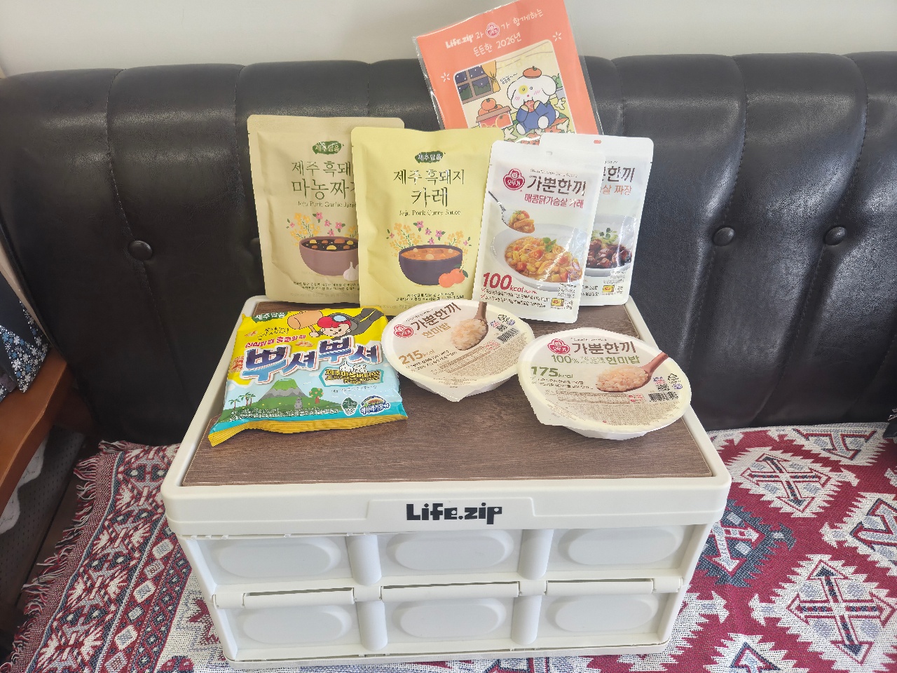 소파 앞 수납함 위에 전시된 한식 간식과 카레, 요리책