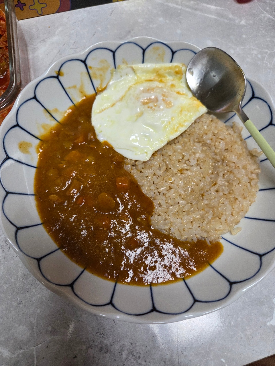 식탁에 차려진 계란후라이, 밥, 카레의 한 끼 식사