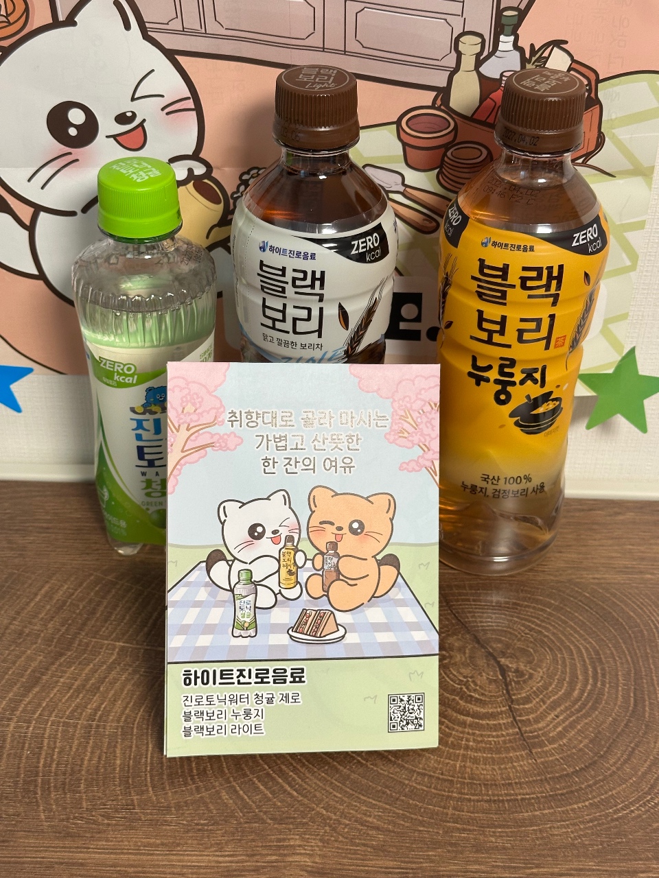 음료 병과 포장지, 캐릭터 인형이 함께 전시된 음료 상품 소개
