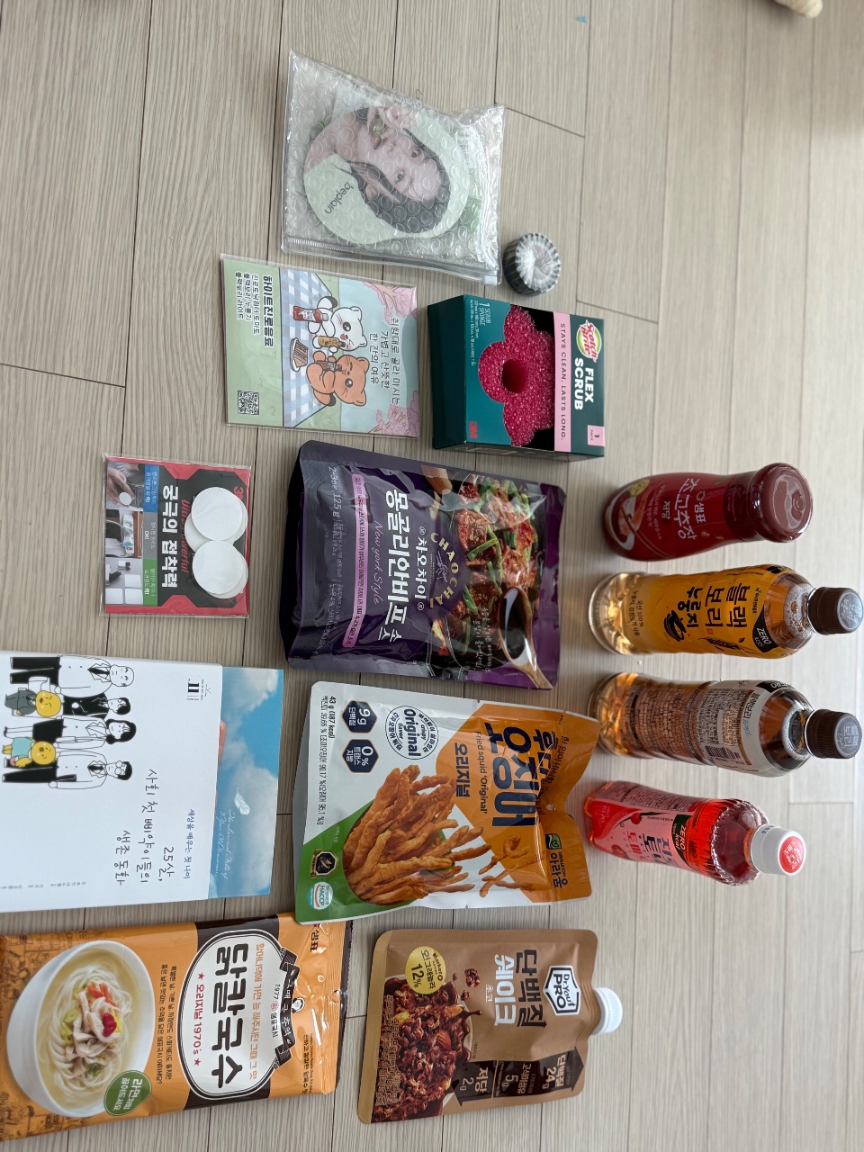 나무 바닥에 펼쳐진 한국 식품, 음료, 생활용품 모음